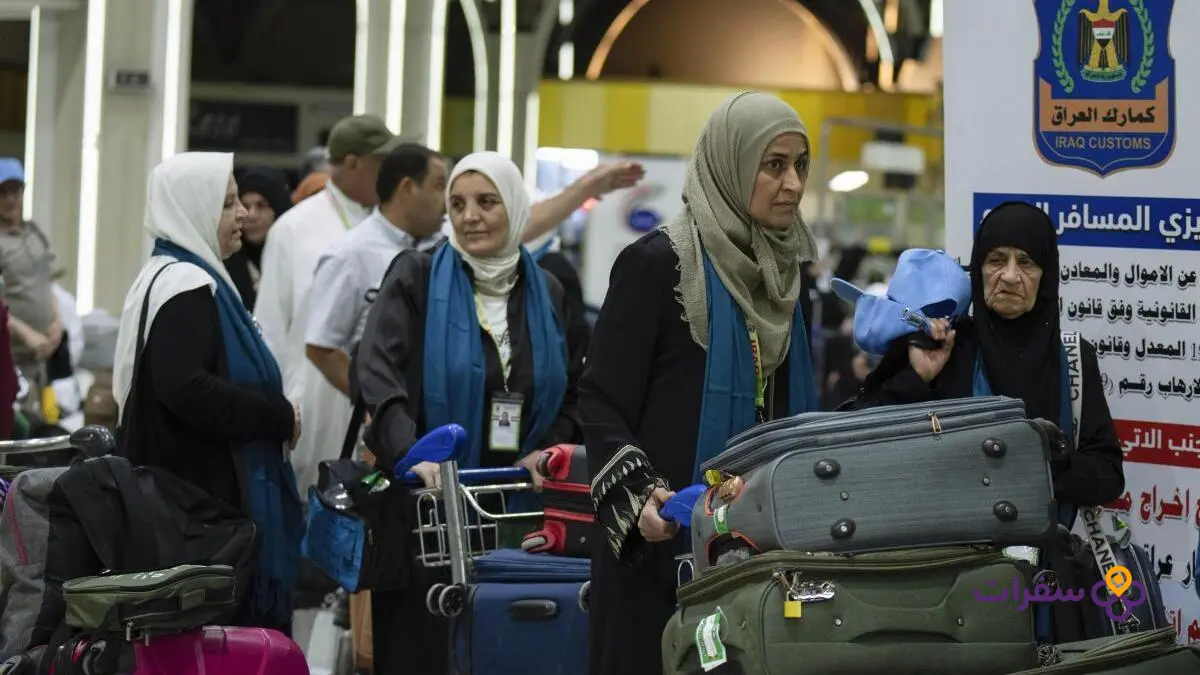 حجاج عراقيون يرتدون ملابس الإحرام البيضاء يقدمون جوازات سفرهم لموظف الجوازات في مطار بغداد الدولي.